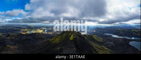Aerial view of sun rays filter through the clouds, illuminating the rugged peaks and still lakes, creating a stunning contrast of light and shadow, Ic Stock Photo