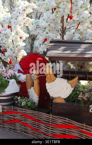 Decorative Easter egg display with wooden chickens and floral background in spring setting. Stock Photo