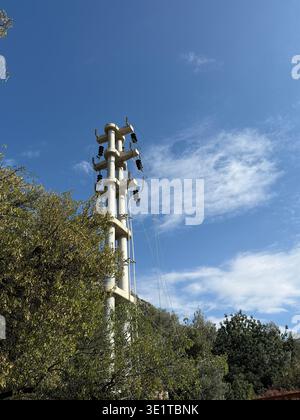 Cell tower against blue sky surrounded by trees used for telecommunications and connectivity. Mobile photo Stock Photo