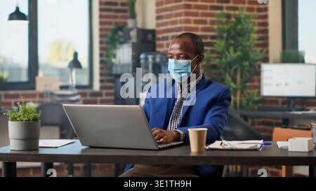 African american consultant analyzing report statistics with email paperwork on laptop. Male employee using data to plan business presentation and project on website browser. Tripod shot. Stock Photo