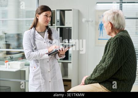 Young Female Doctor Discussing Test Results with Senior Man Stock Photo