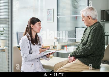 Female Doctor Consulting Senior Man during Medical Appointment Stock Photo