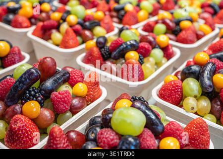 Variety of seasonal summer fresh berries in paper boxes selling at the market. Assorted paper containers of berries for sale at a market. Healthy frui Stock Photo