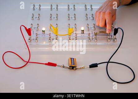 Educational kit for experiments with electrical circuits. A transparent board with terminals for connecting components. The light bulbs are connected Stock Photo