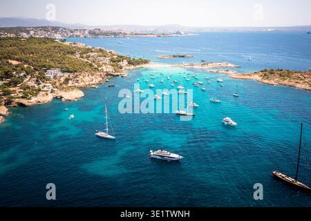 Aerial view of boats floating on the turquoise waters near the rocky coast of Mallorca, Balearic Islands, Spain. Stock Photo