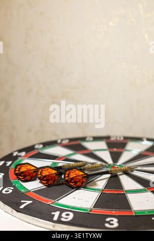 Three darts precisely hitting the target on a traditional dartboard with red-green segments. Blurred background emphasizes accuracy and skill. Stock Photo