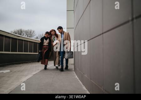 Three colleagues walking together outdoors having a casual business meeting and friendly conversation Stock Photo