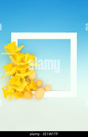 Easter egg and yellow daffodil flower decorative background border on gradient blue with white square frame. Seasonal symbols for festive  season. Stock Photo
