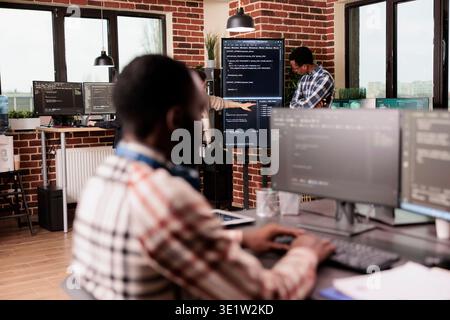 Diverse system engineers working on it project for the company network technology, utilizing their expertise in coding systems. Software developer programming big data in agency office. Stock Photo
