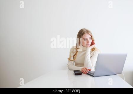 Thoughtful woman working on laptop at home. Online work, decision making and focused productivity concept with copy space. Stock Photo