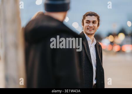 Two business associates smiling and talking on an urban street at dusk Stock Photo