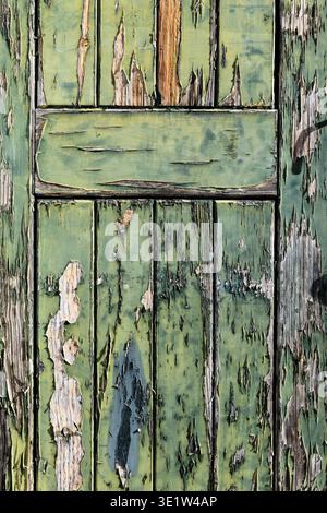 Abstract, closeup detail of a colorful, cracked and peeling, green, wooden doorway in the historic Alfama neighborhood of Lisbon, Portugal. Stock Photo