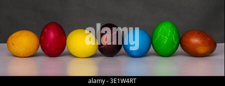 Easter eggs painted in different colors with custom patterns, lined up in a row on a gradient background, a symbol of the holiday, front view Stock Photo