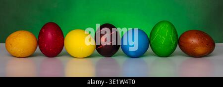 Easter eggs painted in different colors with custom patterns, lined up in a row on a gradient background, a symbol of the holiday, front view Stock Photo