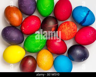 Easter eggs painted in different colors, custom patterns on a white background, top view Stock Photo