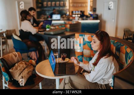 Business workers in a cafe working on laptops and drinking coffee during a remote meeting Stock Photo