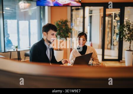 Business coworkers discussing project ideas over a laptop in a modern office lounge Stock Photo