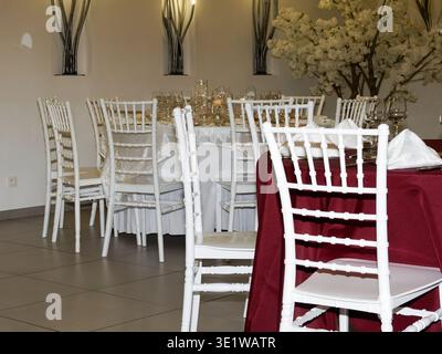 Elegant wedding reception setup with decorated tables and white chairs in a banquet hall, ready for guests and a formal celebration event. Stock Photo
