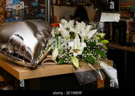 Bouquet of white lilies (Lilium) with greenery and baby’s breath, arranged as elegant floral decoration for special occasion. Stock Photo