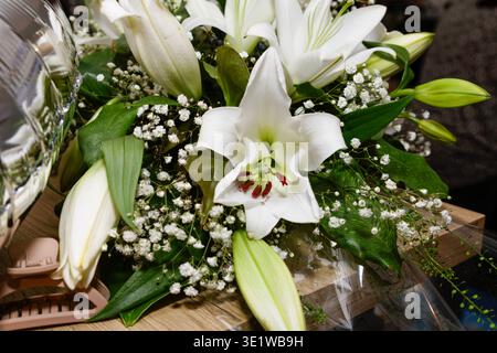 Bouquet of white lilies (Lilium) with greenery and baby’s breath, arranged as elegant floral decoration for special occasion. Stock Photo