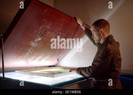 Young Adult Man Operating Screen Printing Equipment in Workshop Stock Photo