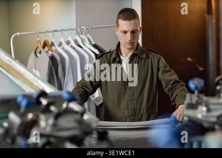 Young Man Working in Textile Factory Preparing Fabric for Production Stock Photo