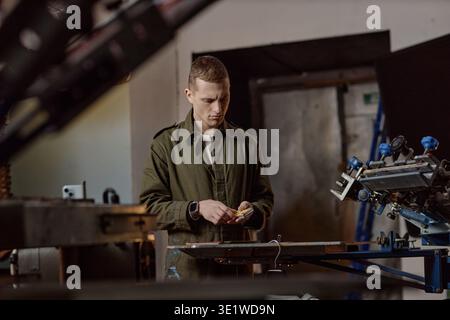 Young Man Operating Printing Equipment in Industrial Workshop Stock Photo