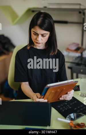 Women working on tablet and laptop in home office concentrating on documents and remote study Stock Photo
