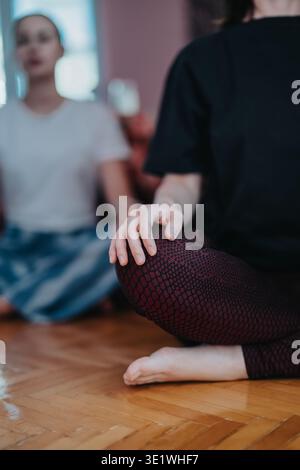 Two women practicing seated meditation and mindfulness at home in comfortable casual clothing Stock Photo