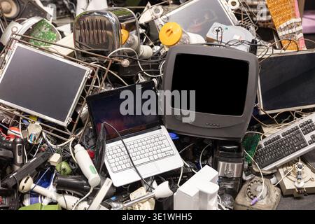 A pile of discarded electronic waste is shown including a laptop television keyboard and other obsolete devices. This image can be used for concepts r Stock Photo