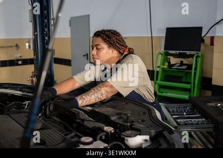 Dedicated mechanic works on engine, showing talent in a modern repair garage setting Stock Photo