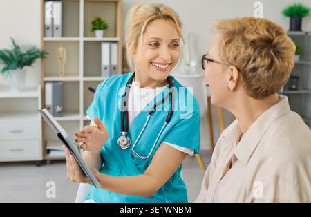 Nurse using tablet to show good health news to older woman on consultation Stock Photo