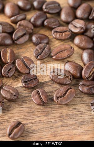 Fresh dark roasted Robusta and Arabica coffee beans closeup scattered on rustic wooden table. Coffee shop background with copy space.  Best blend of c Stock Photo