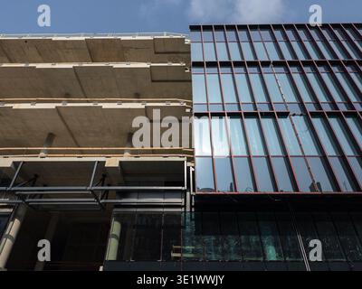 Modern office building under construction showing concrete floors and glass curtain wall facade, urban architecture and structural development process Stock Photo