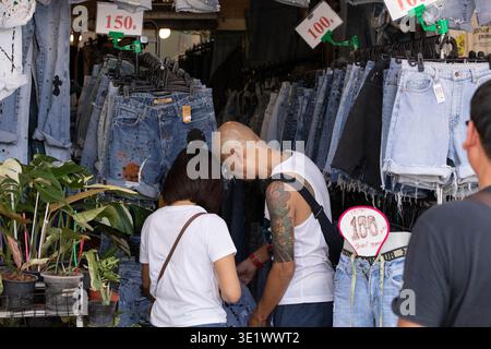 BANGKOK, THAILAND-MAR 1, 2026: Tourist couple shopping, ordinary moment in Asian community market, rear view, at Chatuchak Market. Stock Photo