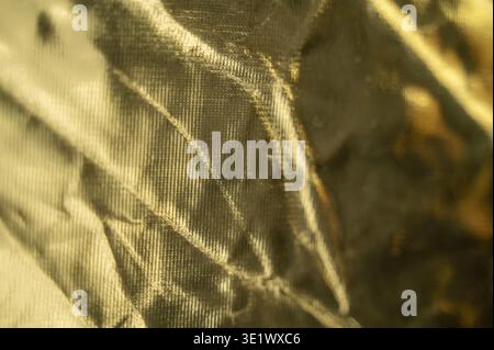 Shiny yellow material background featuring smooth textile waves. Concept of seasonal spring decoration, warm golden atmosphere, and minimalist cloth s Stock Photo