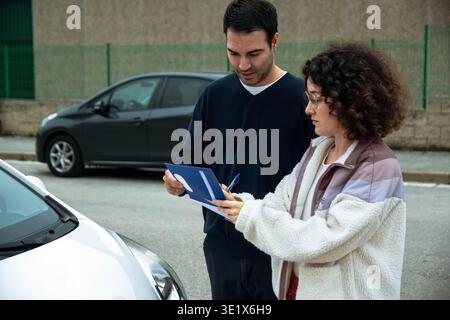 Driving instructor teaching student how to fill out documents Stock Photo