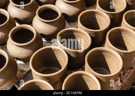 A collection of freshly thrown clay pots and jars of various shapes sits in the sun to dry at a traditional pottery workshop located in Udaipur. Udaip Stock Photo