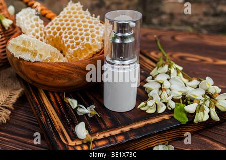 Fragrant flowers bloom on the tree while bees gather nectar, supporting the creation of honey. The scene shows honeycomb pieces placed on a wooden sur Stock Photo