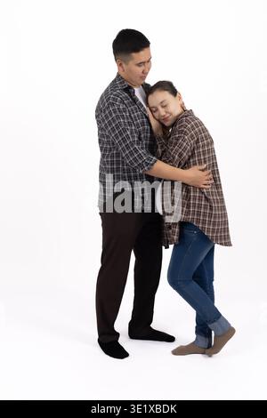 Young couple in checkered shirts hugging on white background Stock Photo