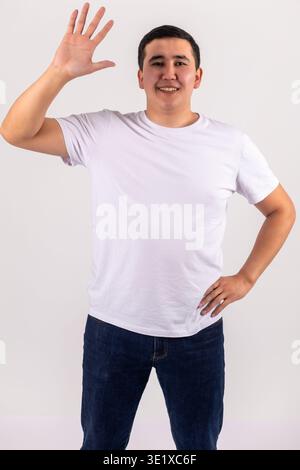 Young man in white t-shirt waving hello and smiling Stock Photo