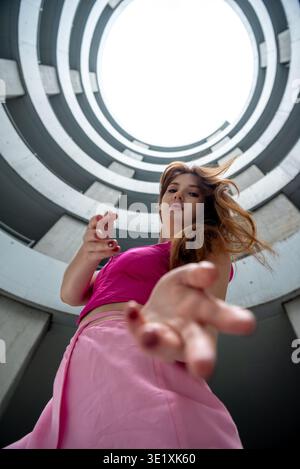 Beautiful Gen Z woman in pink outfit doing dance moves, low angle view Stock Photo