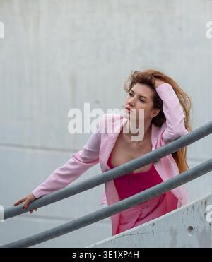 Woman leaning on rail and thinking, portrait in a concrete building Stock Photo