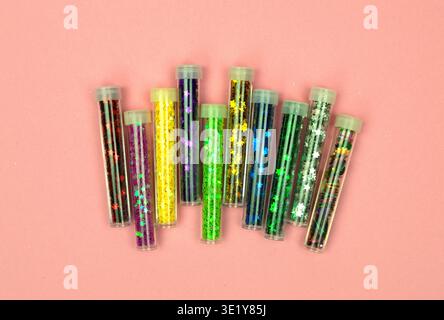 A mesmerizing array of colorful sequins in mini jars, beautifully arranged on a pastel pink background for a dreamy look. Stock Photo