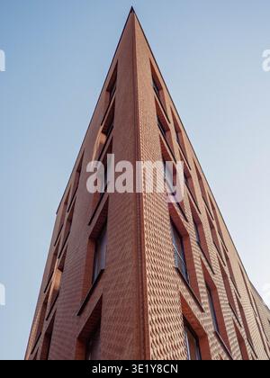Modern red brick building with textured facade and angular corner rising against clear sky in Rottermani district, Tallinn Stock Photo