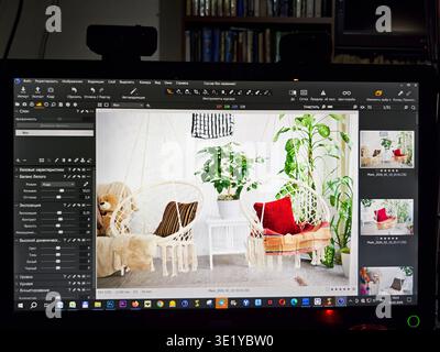 Kirov, Russia - February 10 2026: A person edits a design project using software on a computer. The screen shows a cozy interior with plants and comfo Stock Photo