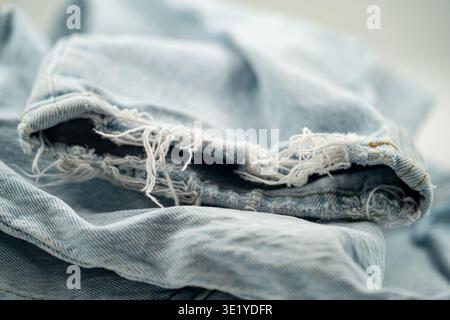 Close up of frayed denim hem with loose threads and worn edges. Stock Photo