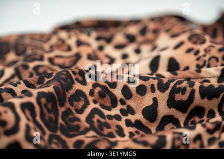 Close up of leopard print fabric texture with soft folds and pattern. Stock Photo