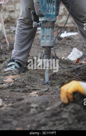 Construction worker uses jackhammer on ground surface Stock Photo