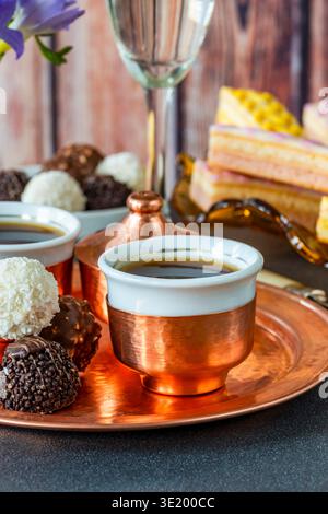 Coffee and selection of gourmet cakes and chocolate truffles set up on a table Stock Photo
